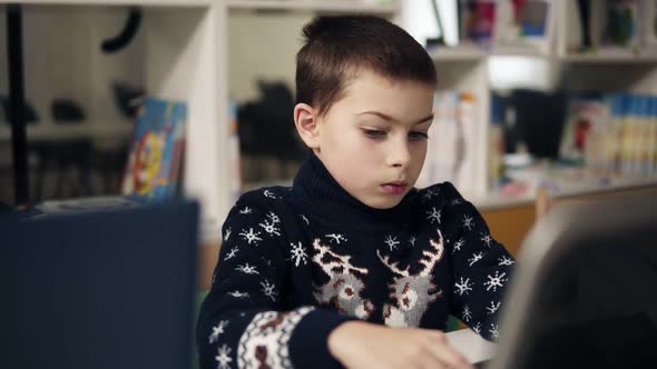 Slowmotion Footage of a Little Boy with Big Blue Eyes Portrait Sitting in Front of the Laptop Screen