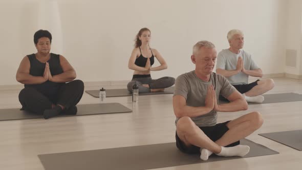 Multiethnic Seniors and Yoga Coach Meditating Together