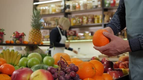 Closeup of a Male Salesman Holding a Fresh Orange a Health Food Store