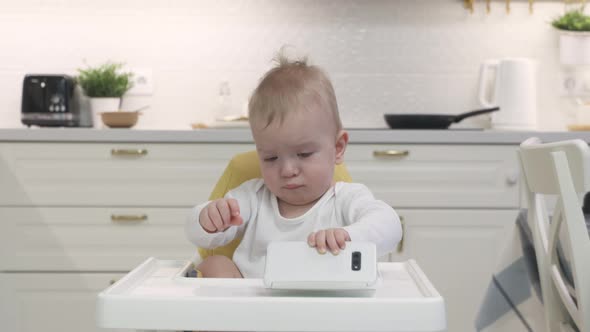 Baby Boy Sitting on High Chair for Babies Playing with Smartphone Cute Toddler Holding Mobile Phone