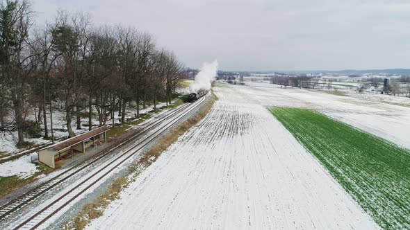 Ariel View of a Steam Engine and Passenger Cars Puffing Along Amish Farm Lands After the First Snow