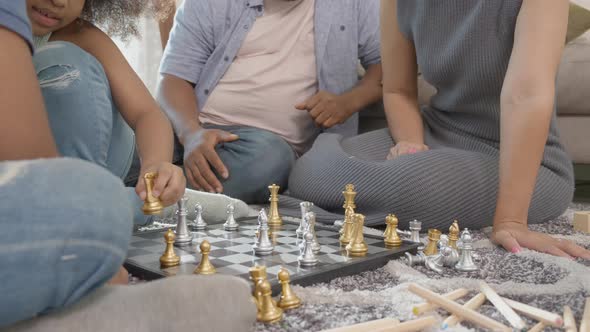 Happiness family with father and mother playing chess with children on floor together with fun.