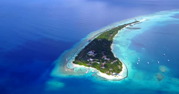 Daytime flying travel shot of a white paradise beach and blue water background in colourful 4K