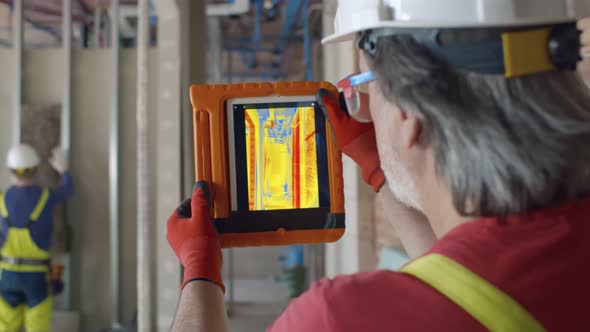 Builder Using Thermal Camera on Tablet on Construction Site