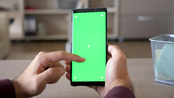 Man Holding a Smartphone in Hands with Green Screen Chroma Mock Up