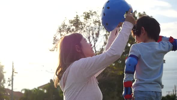 Asian Mother Helping Her Son Putting His Roller Skates On Enjoying Time Together In The Park