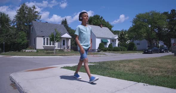 Young african american boy walking down the street listening to music