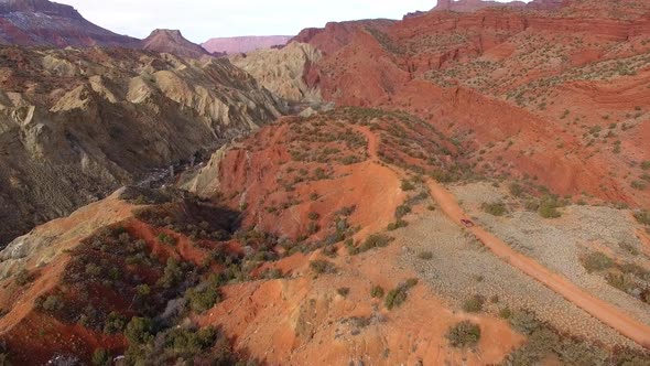 Aerial view following truck driving over winding dirt road on hill top