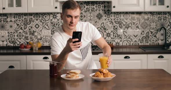 Pensive Man Using Smartphone in Kitchen