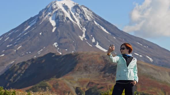 Woman Taking Selfie Photo and Standing on Background of Mountains on Kamchatka Peninsula in Autumn