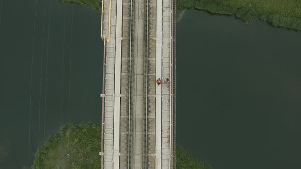 Aerial View of Two People Walking on a Bridge Over a River