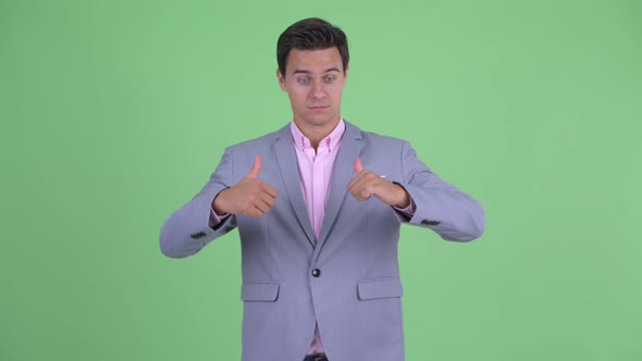 Confused Young Businessman Choosing Between Thumbs Up and Thumbs Down