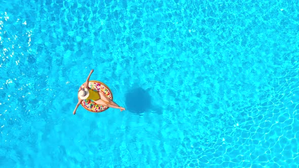 Aerial View of a Woman in Yellow Swimsuit Lying on a Donut in the Pool