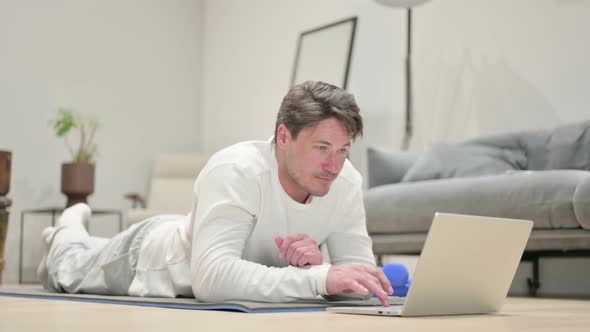 Man Using Laptop on Yoga Mat at Home