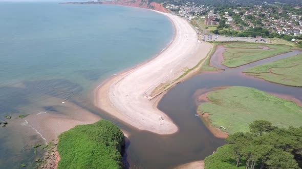 4K Aerial, flying over River Otter, beach, and ocean toward coastal town in England