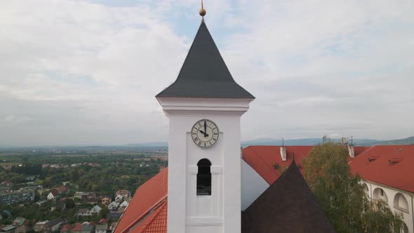 Drone Flies Over Clock Tower in Medieval Castle on Mountain in Small European City at Cloudy Autumn