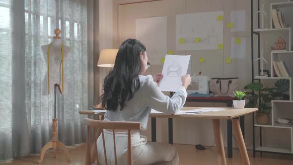 Woman Designer Positively Shaking Her Head While Looking At Hand Bag Sketching On The Layout Bond