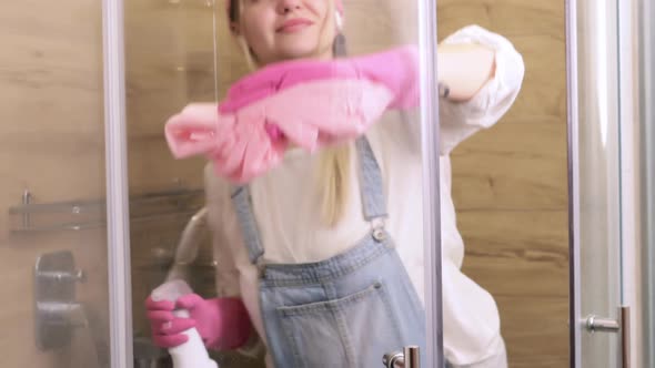 A Beautiful Housewife Cleans the Glass of the Shower Cabin From Plaque