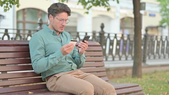 Man having Online Payment Failure on Smartphone in Park Bench