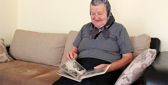 Happy Grandma Looking Photo Album and Smiling