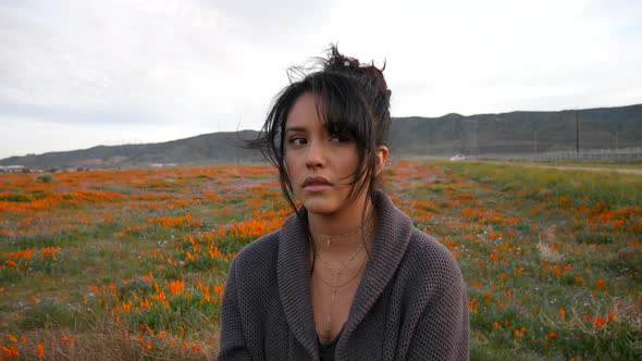 A beautiful young woman looking emotional and sad, crying and sitting alone in a rural field of wild