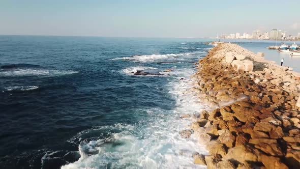 Beautiful and mesmerizing clip of waves and white foam washing over the rocky breakwater of Jaffa ha