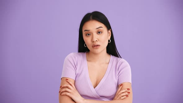 Displeased Asian brunette woman wearing purple t-shirt showing blah blah gesture