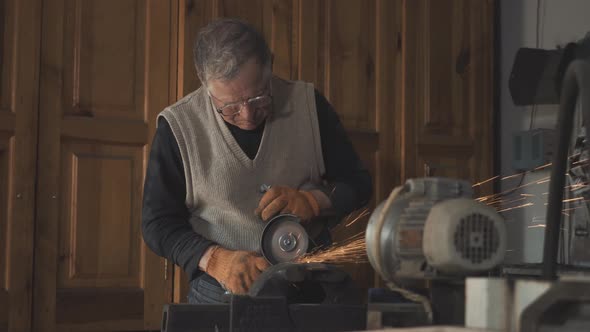 Old Serious Caucasian Man in Eyeglasses Working with Manual Grinding Machine. Concentrated