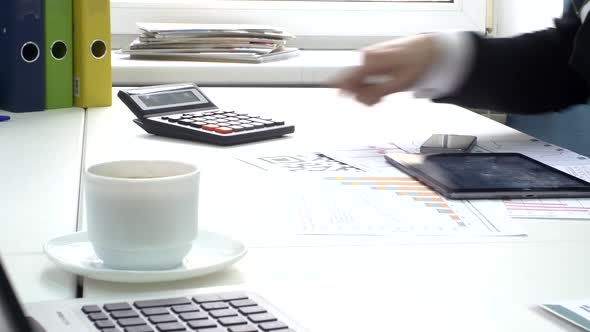 Businessman Works at Her Workplace with Digital Tablet Computer and Calculator