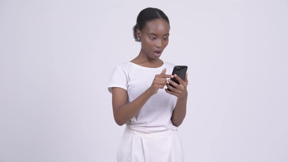 Young African Woman Looking Shocked and Stunned While Using Phone