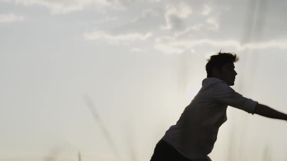 Slow motion shot of young man dancing outdoors against sun