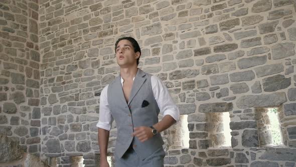 Attractive young fashion man in a suit runs down the stairs in an old fortress. Slow motion