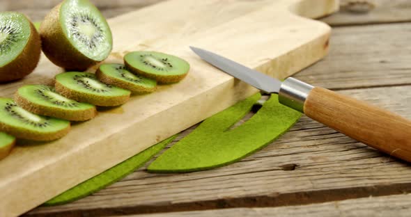 Slices and half section of kiwi on chopping board