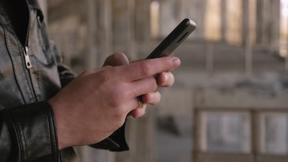 Closeup of a Man's Hand with a Phone Against the Background of an Old Building