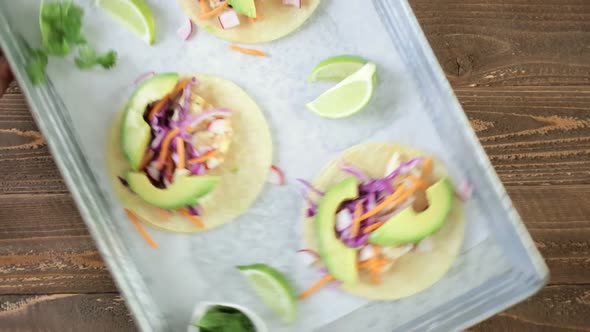 Fresh fish tacos with cod and purple cabbage on a white corn tortillas.