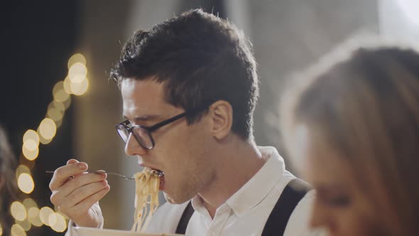 Close Up Portrait of Young Hipster Guy Eating at Table at Party or Celebration