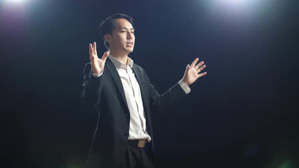 Side View Of Asian Speaker Man In Business Suit Holding His Hands Together While Speaking