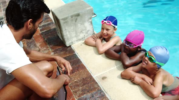 Coach giving swimming lesson to his students