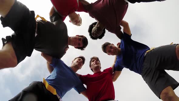 A group of young men playing flag football on the beach.