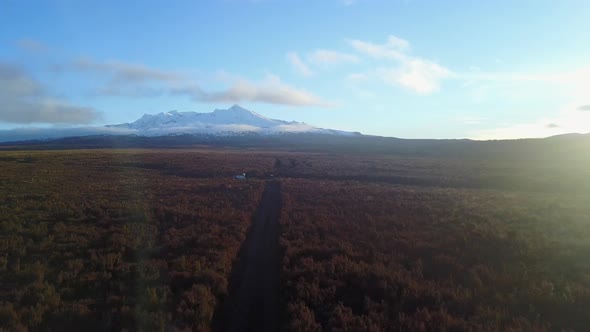 Aerial shot showing a snowy mountain with brown shrubs. New Zealand