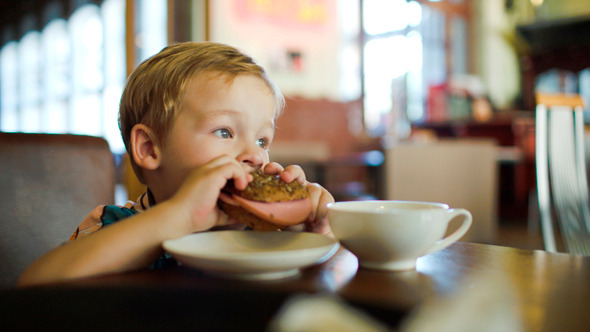 Little Boy Eating Sandwich In A Cafe