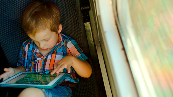 Boy In Train Using Tablet Computer
