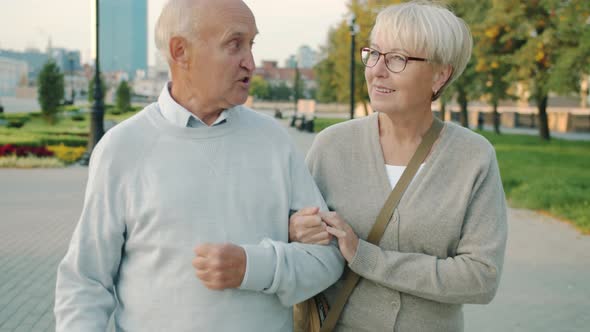 Slow Motion of Cheerful Couple of Senior People Walking in City Talking Enjoying Summer Day