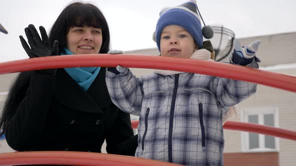 Happy Mother Plays With Her Child On Snow Covered Playground. Slow Motion Winter City 4