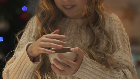 Little Girl in Winter Sweater Warming With Cup of Hot Tea, Awaiting Christmas