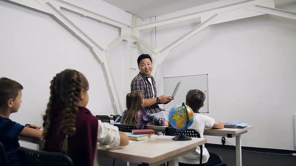 Caucasian Schoolgirl Raising Hand and Answering Question of the Korean Teacher