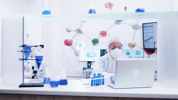 Female Scientist in Protection Gear Typing on Computer