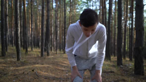 Young Fit Caucasian Boy Jogging on Woods Road and Stopped To Catch a Fresh Breath