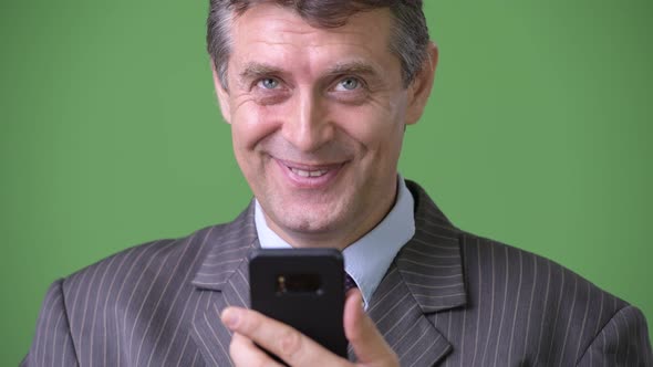 Mature Handsome Businessman Against Green Background