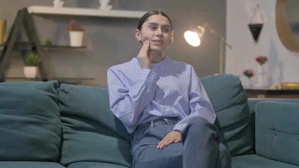 Hispanic Woman having Neck Pain while Sitting on Sofa